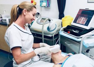 Fiona in white applying treatment to patient